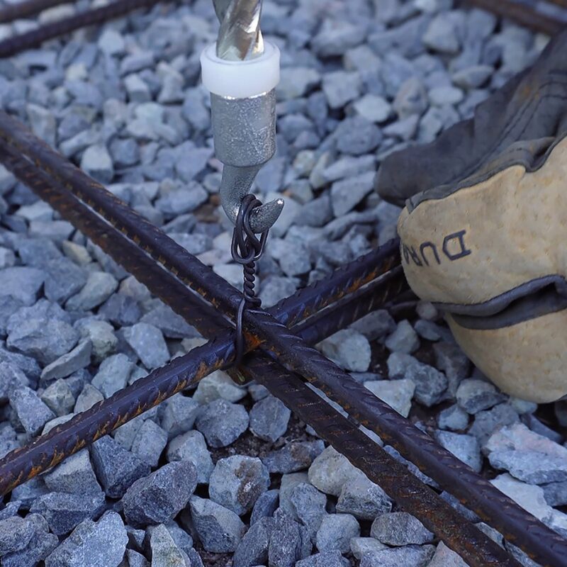 Black rod tying tool being used to secure metal rebar for garden structures or fencing installation.