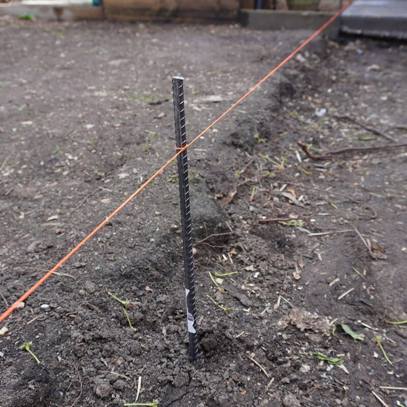Bundle of 600mm 12mm reo bars laid out in backyard for use as structural supports in garden construction projects.